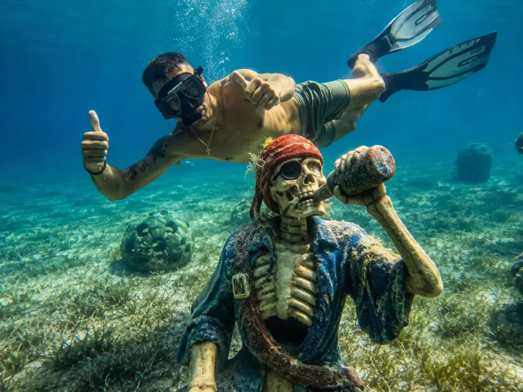 Snorkeler exploring an underwater sculpture in clear shallow water at Pearl Island, Bahamas